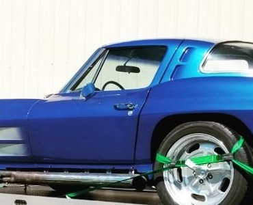 Blue classic coupe strapped down on a flatbed deck